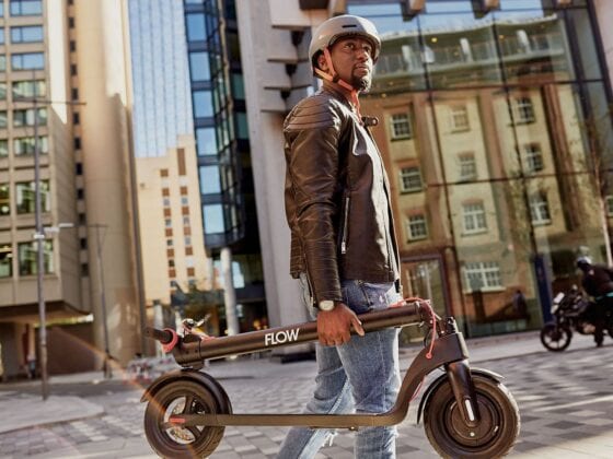 Man carrying Flow electric scooter in city