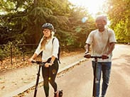 girl and boy riding Flow Electric Scooters in a park